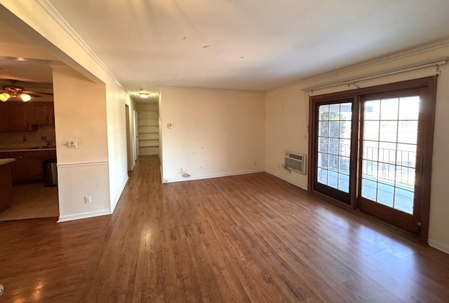 spare room with sink, ceiling fan, a wall mounted AC, wood-type flooring, and ornamental molding