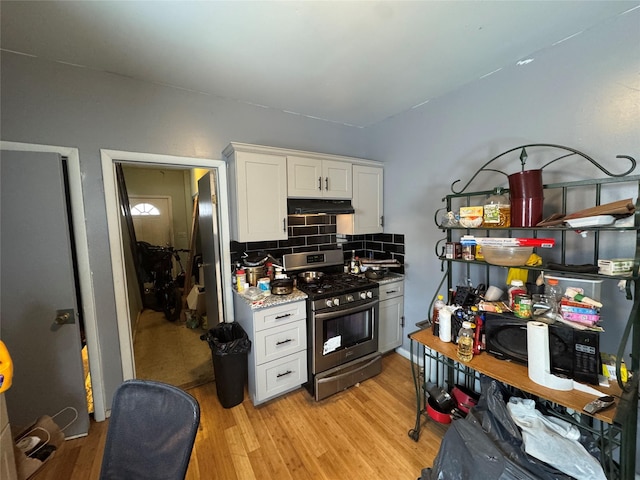 kitchen featuring tasteful backsplash, stainless steel range with gas stovetop, light wood-type flooring, and white cabinets