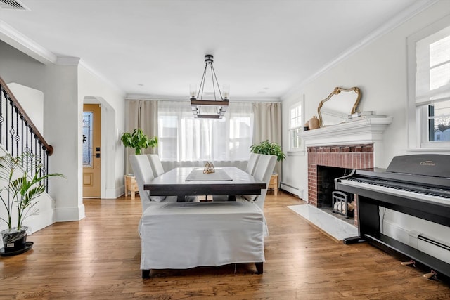 dining area with wood-type flooring, ornamental molding, and baseboard heating