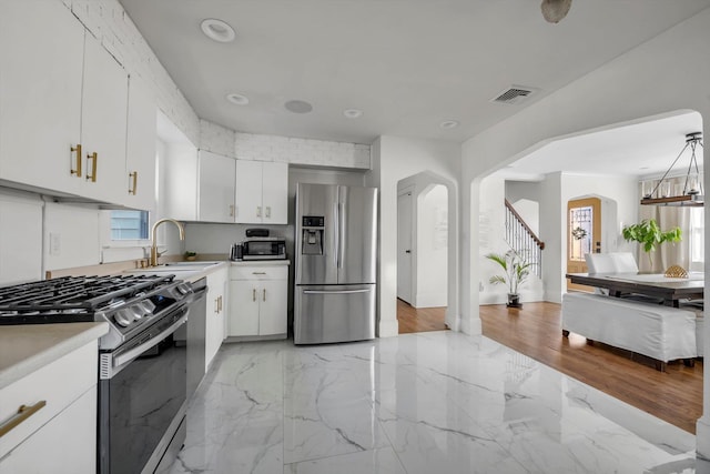 kitchen featuring stainless steel appliances, white cabinetry, sink, and decorative light fixtures