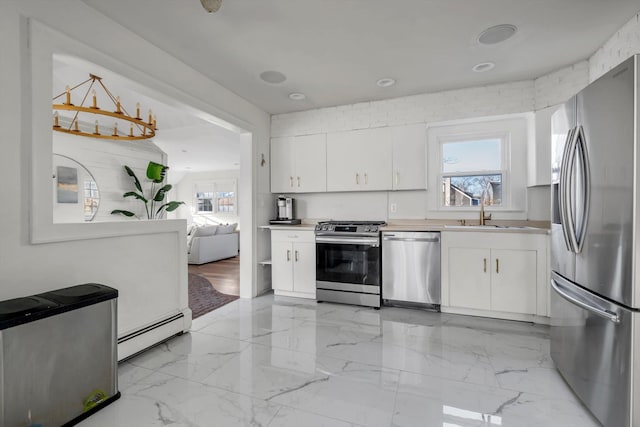 kitchen with sink, a baseboard radiator, appliances with stainless steel finishes, a healthy amount of sunlight, and white cabinets