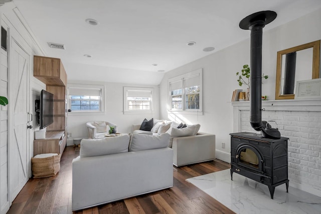 living room featuring dark hardwood / wood-style flooring, lofted ceiling, and a wood stove