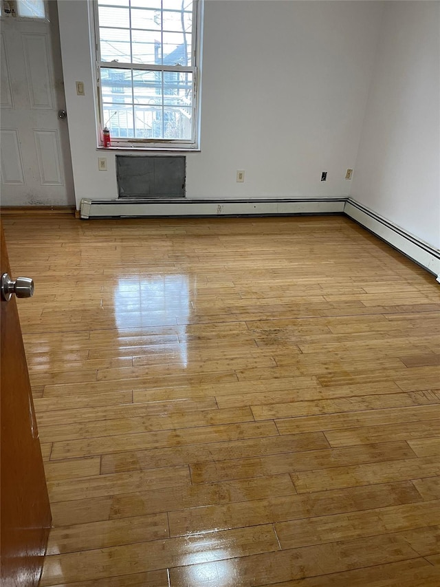 spare room with a baseboard heating unit and light wood-type flooring