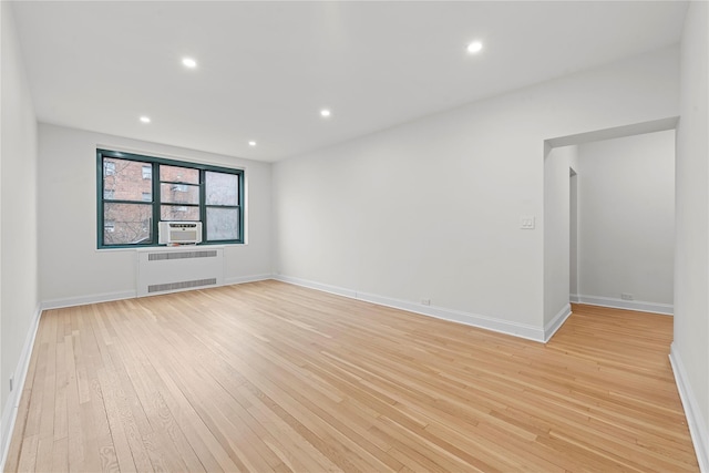 empty room with cooling unit, radiator, and light hardwood / wood-style floors