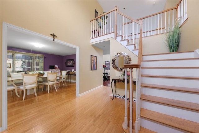 staircase with hardwood / wood-style flooring and a towering ceiling