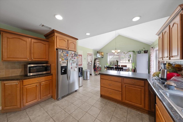 kitchen featuring appliances with stainless steel finishes, lofted ceiling, sink, backsplash, and a notable chandelier