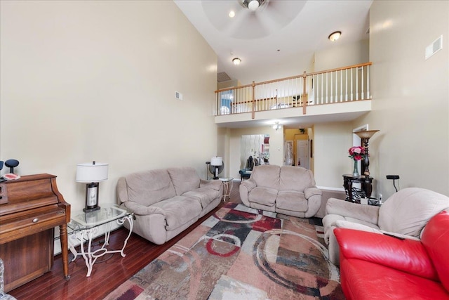 living room with ceiling fan, a towering ceiling, and dark hardwood / wood-style flooring