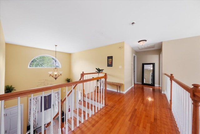 corridor with an inviting chandelier and light hardwood / wood-style flooring