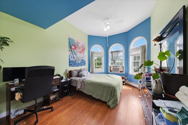 bedroom featuring cooling unit, a baseboard radiator, and hardwood / wood-style floors