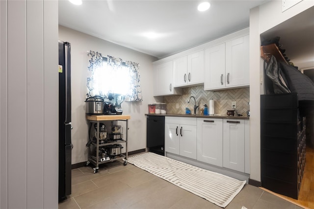 kitchen with sink, light tile patterned floors, white cabinetry, tasteful backsplash, and black appliances