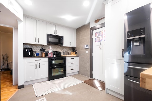 kitchen featuring backsplash, light tile patterned floors, black appliances, and white cabinets