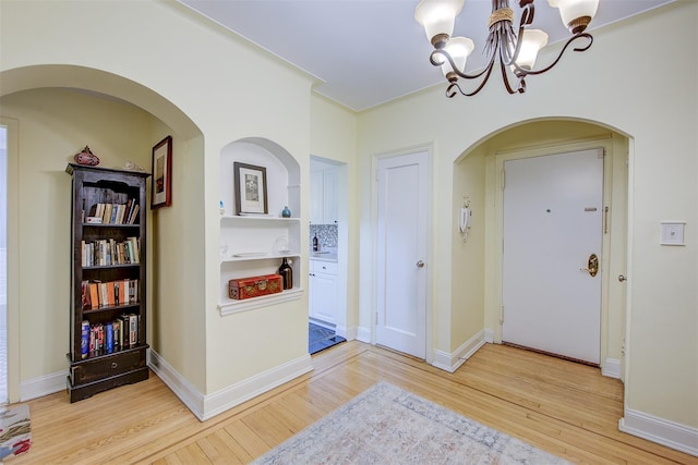 hall with a chandelier and light wood-type flooring