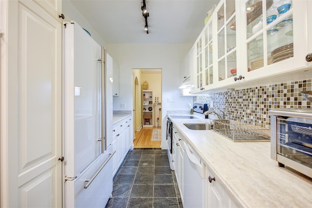 kitchen featuring sink, backsplash, white cabinets, and white appliances