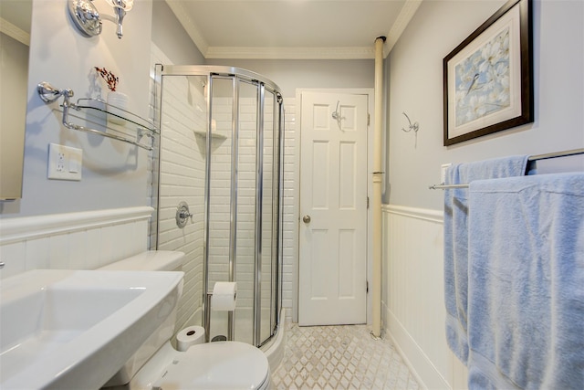 bathroom with crown molding, toilet, a shower with shower door, and sink