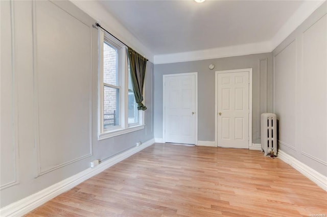 empty room featuring radiator and light hardwood / wood-style flooring