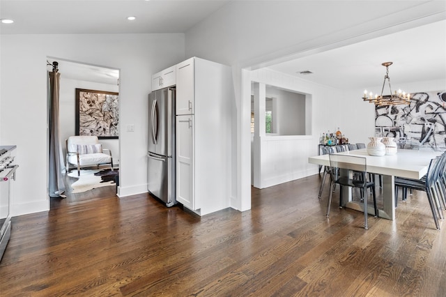 dining area with lofted ceiling, dark hardwood / wood-style floors, and an inviting chandelier