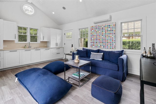 living room with sink, a wall unit AC, high vaulted ceiling, and light wood-type flooring