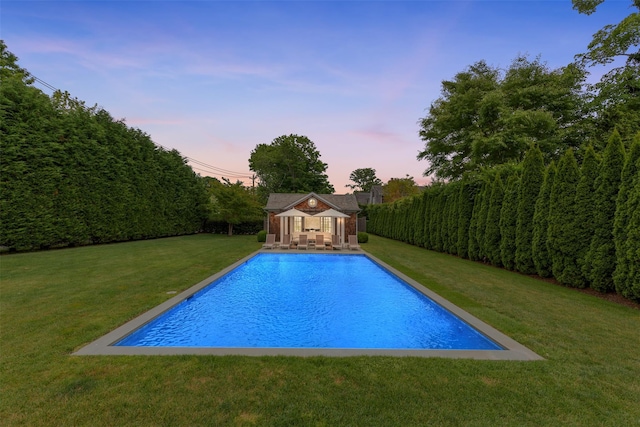 pool at dusk with a yard and an outdoor structure