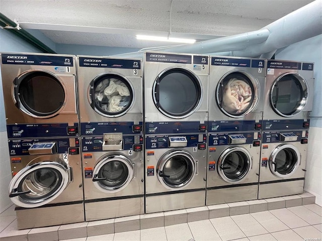 washroom featuring stacked washer and dryer, washing machine and dryer, tile patterned flooring, and a textured ceiling