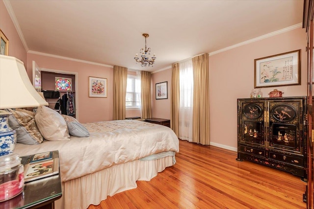 bedroom featuring crown molding, a walk in closet, hardwood / wood-style floors, and a notable chandelier