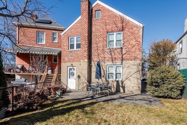 rear view of property with a patio area, solar panels, and a lawn