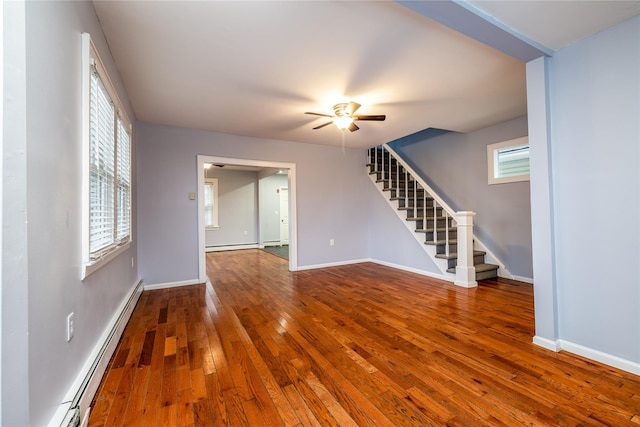 unfurnished living room with hardwood / wood-style flooring, a baseboard heating unit, a wealth of natural light, and ceiling fan