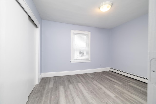 unfurnished bedroom featuring a baseboard radiator, light wood-type flooring, and a closet