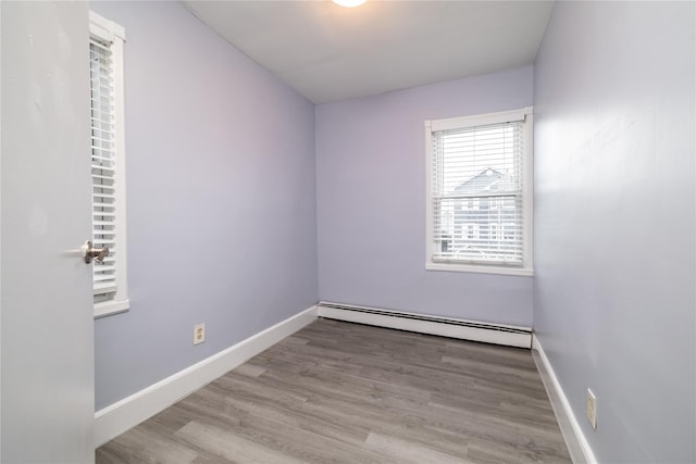 unfurnished room featuring a baseboard heating unit and light hardwood / wood-style flooring