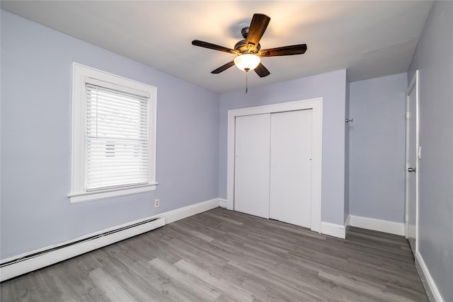 unfurnished bedroom featuring hardwood / wood-style flooring, ceiling fan, baseboard heating, and a closet