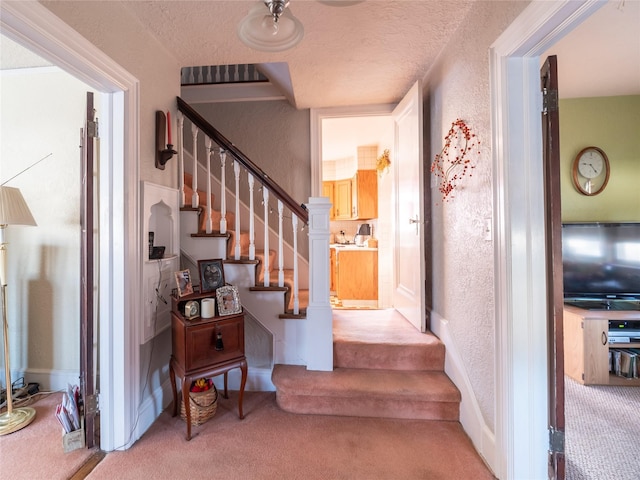 staircase featuring carpet and a textured ceiling