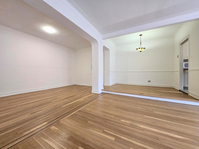 unfurnished room featuring beamed ceiling, crown molding, and hardwood / wood-style floors