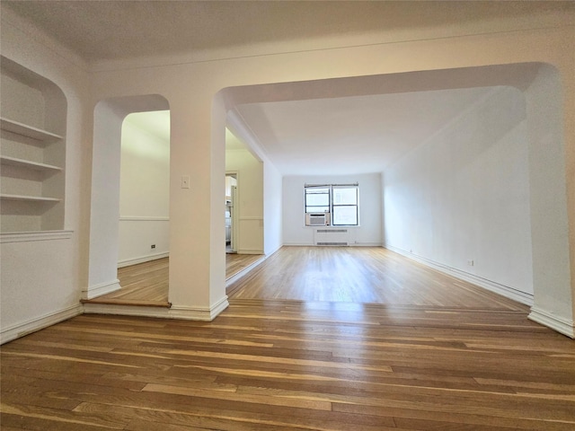 unfurnished room featuring built in shelves and dark hardwood / wood-style floors