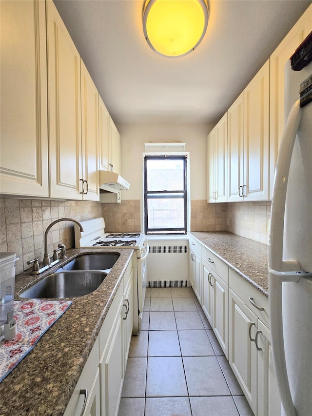 kitchen with sink, white gas stove, white cabinetry, fridge, and radiator