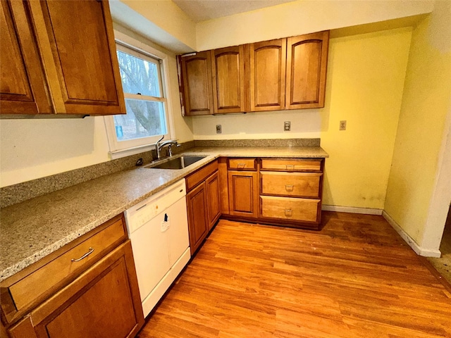 kitchen featuring dishwasher, light stone countertops, sink, and light hardwood / wood-style flooring