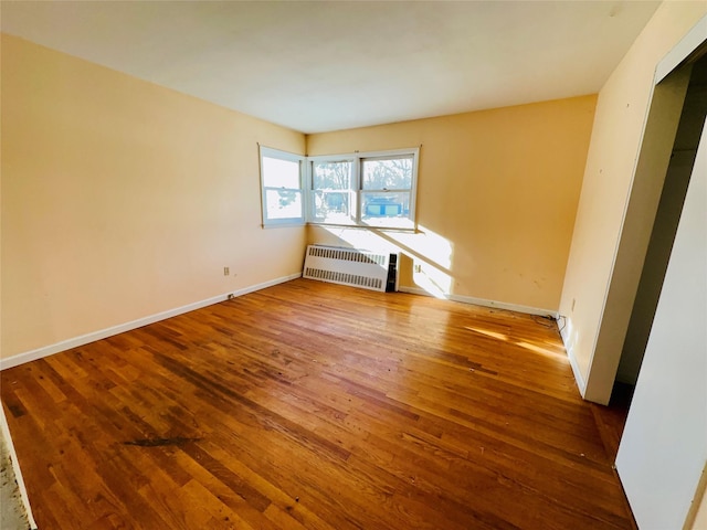 spare room featuring radiator and hardwood / wood-style floors