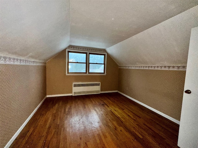 bonus room with lofted ceiling, radiator heating unit, dark hardwood / wood-style floors, and a textured ceiling