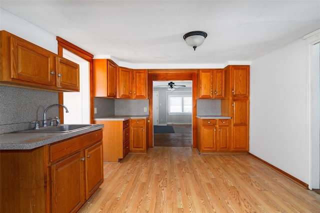 kitchen featuring tasteful backsplash, ceiling fan, sink, and light wood-type flooring