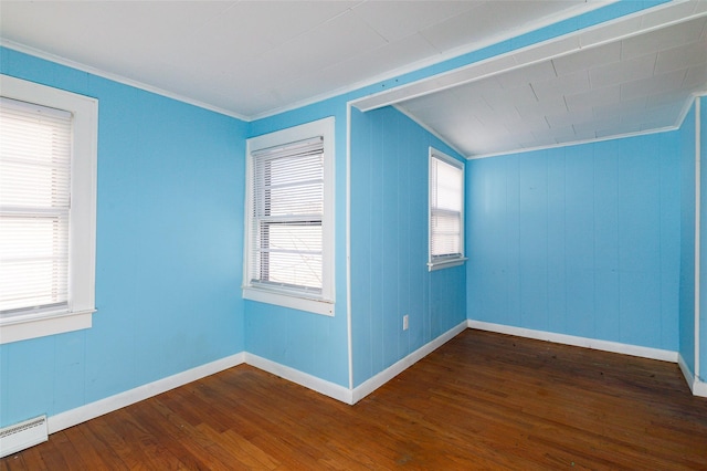 empty room featuring a baseboard heating unit, vaulted ceiling, ornamental molding, and dark hardwood / wood-style floors