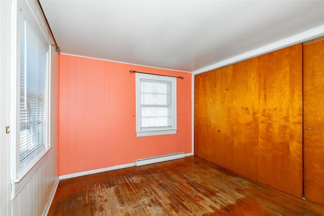 spare room featuring baseboard heating and dark wood-type flooring