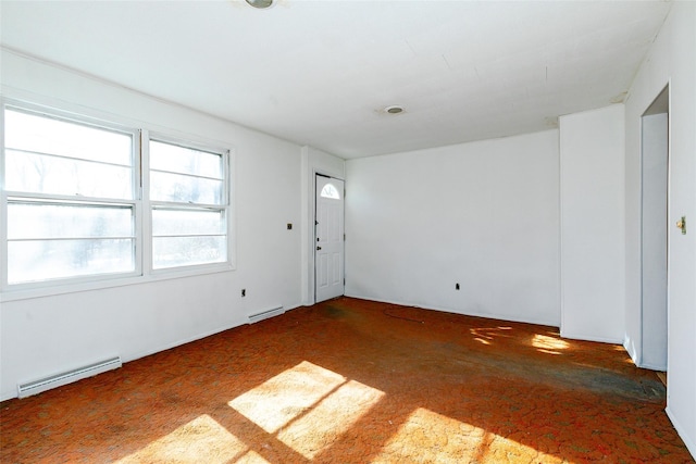 spare room with baseboard heating and dark colored carpet