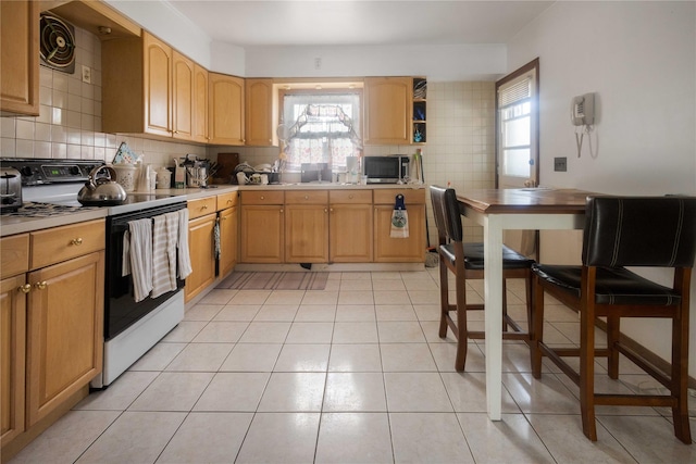 kitchen with range with electric stovetop, tasteful backsplash, a wealth of natural light, and light tile patterned floors