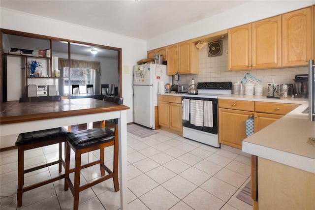 kitchen with tasteful backsplash, light tile patterned floors, and white appliances