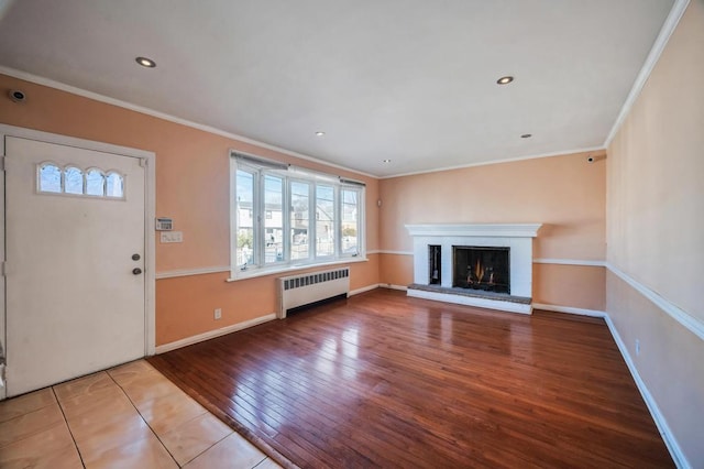 unfurnished living room featuring a healthy amount of sunlight, a brick fireplace, radiator, and crown molding