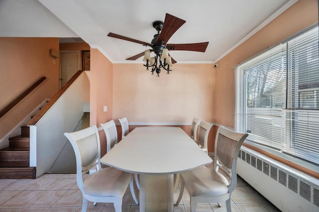 tiled dining space with crown molding, ceiling fan, and radiator heating unit