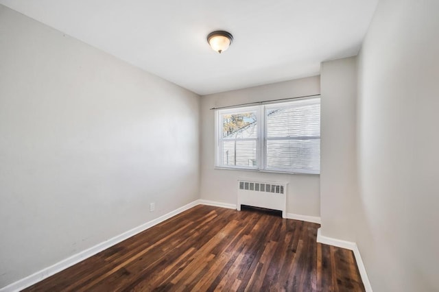 unfurnished room with radiator heating unit and dark hardwood / wood-style floors