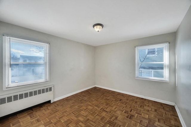 unfurnished room featuring dark parquet flooring and radiator heating unit