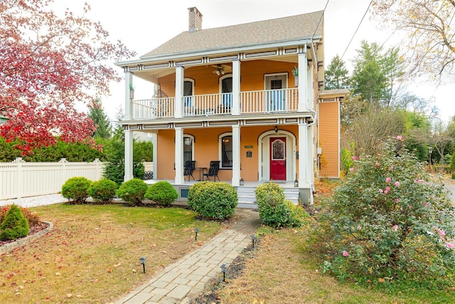 view of front of property featuring a porch, a balcony, and a front yard