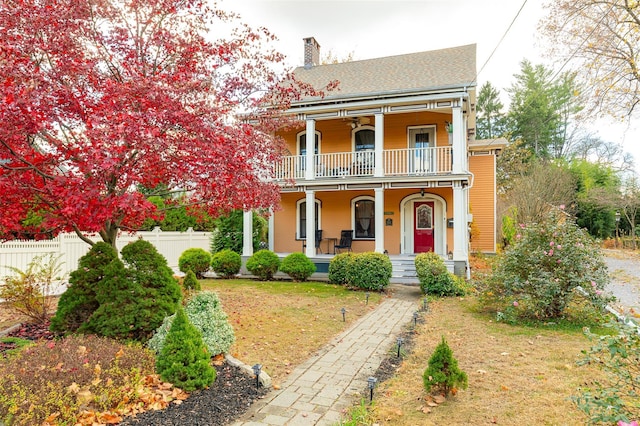 view of front of property with a porch, a balcony, and a front yard