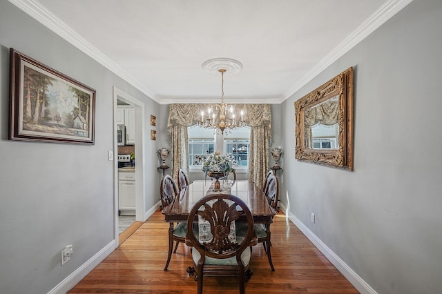 dining room with an inviting chandelier, ornamental molding, and light wood-type flooring