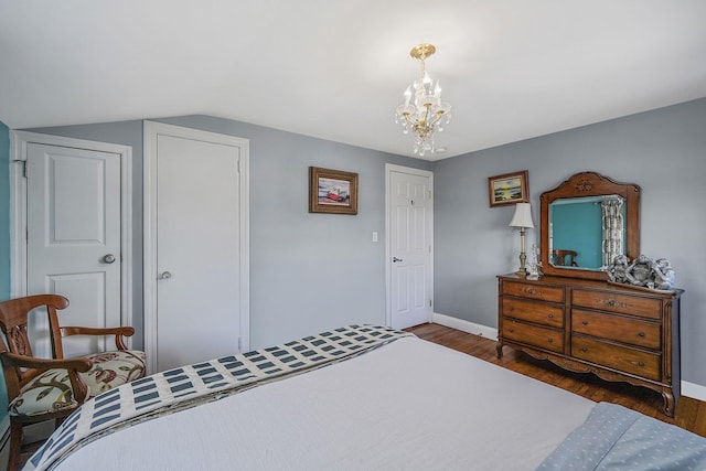 bedroom with lofted ceiling, an inviting chandelier, and dark hardwood / wood-style flooring